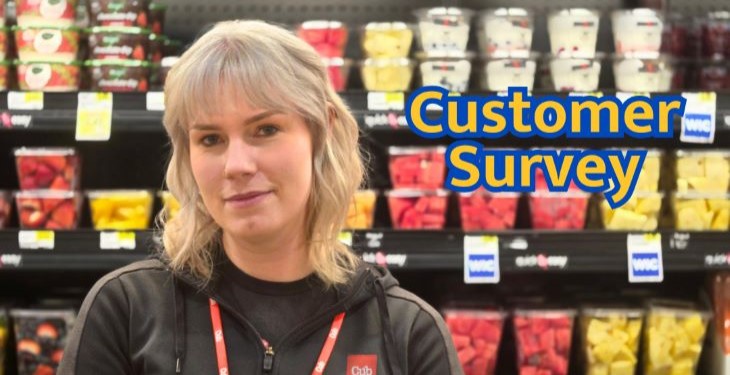 Woman in front of cut fruit shelves at a grocery store.